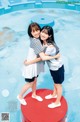 A couple of young women standing next to each other near a pool.