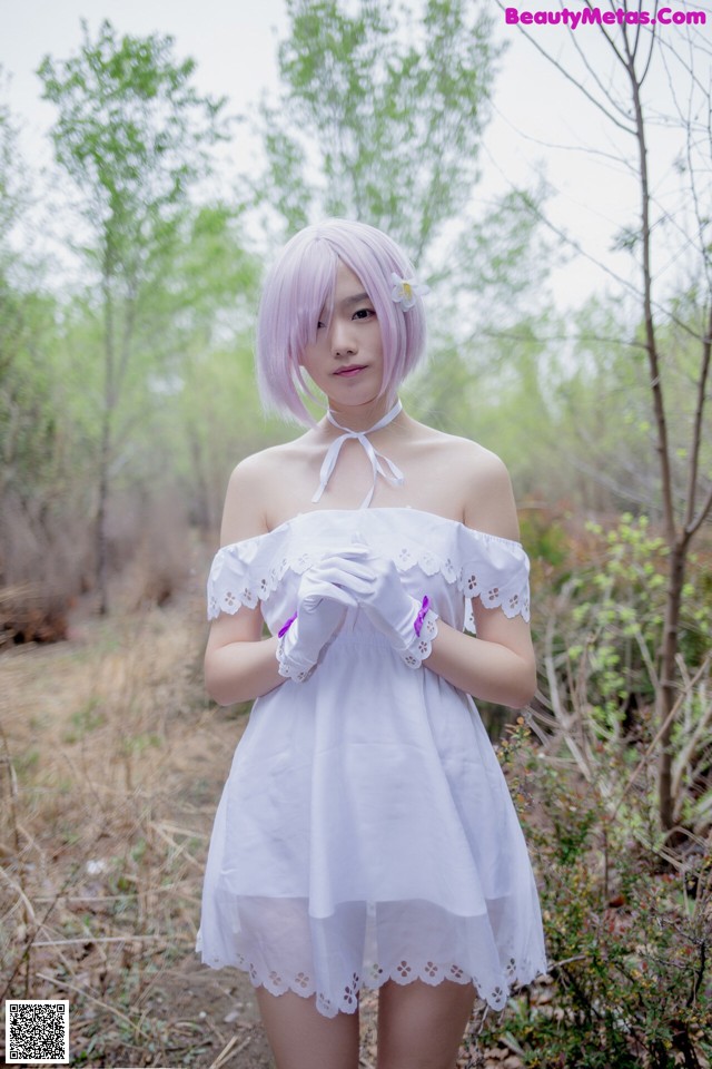 A woman in a white dress standing in the woods.