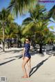 A woman in a polka dot swimsuit standing on a beach.