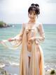 A woman in a kimono standing on a beach next to the ocean.