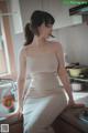 A woman in a white dress sitting on a kitchen counter.