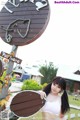 A woman standing in front of a wooden sign.